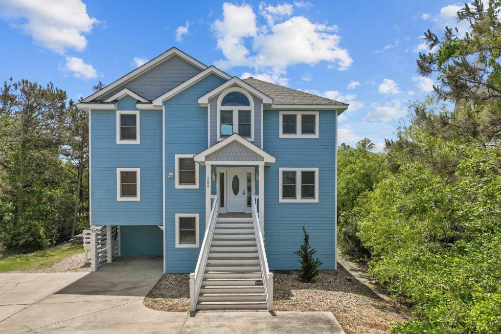 a blue house with a staircase leading up to it at 1090 - Catch Me N Corolla in Corolla