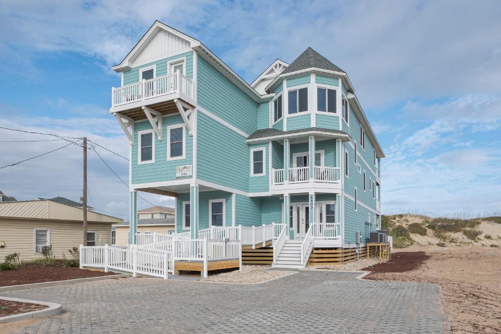 a blue house with white railings on a beach at 5700 - La Cebolla in Nags Head