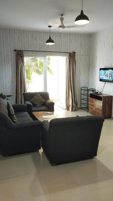 a living room with a couch and a table at Pool View Apartment - Sunshine By Leela Homes in Arpora