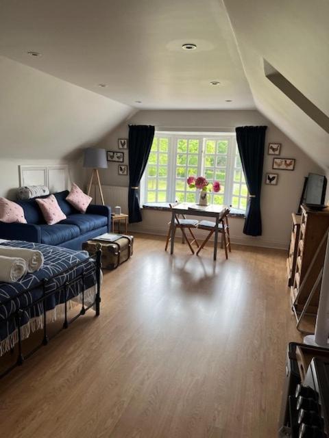 a living room with a blue couch and a table at The Bird Loft Studio in Horsted Keynes