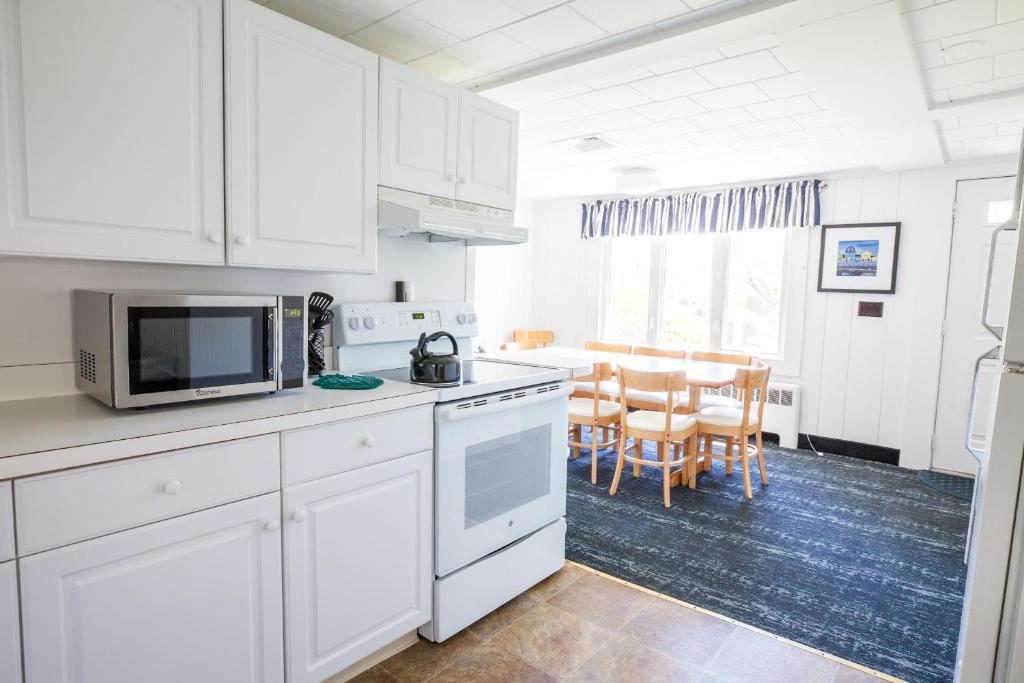 a kitchen with white cabinets and a dining room at Green Harbor Resort in West Yarmouth