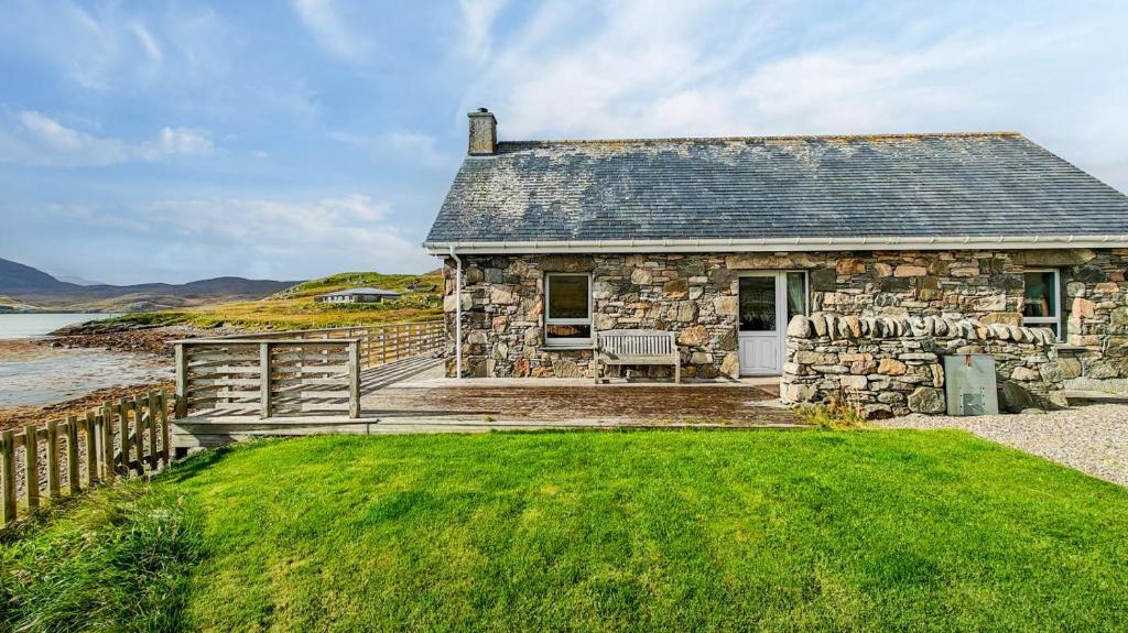 a stone house on the shore of a body of water at 2 Bed in Reef oc-r30133 in Uig