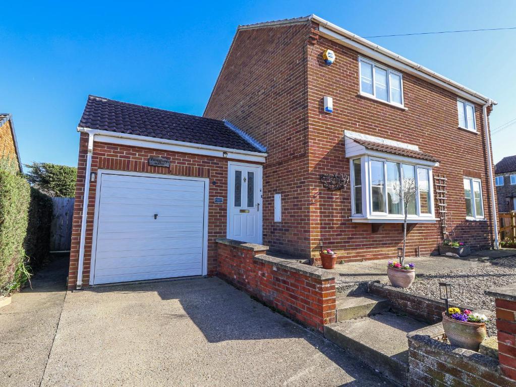 a red brick house with a white garage at Thorntons House in Northallerton
