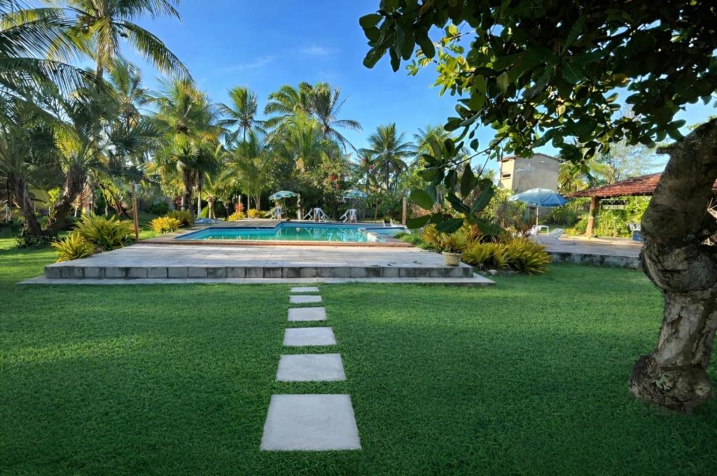 a pathway in the grass in front of a pool at Pousada Taba de Canes in Canavieiras