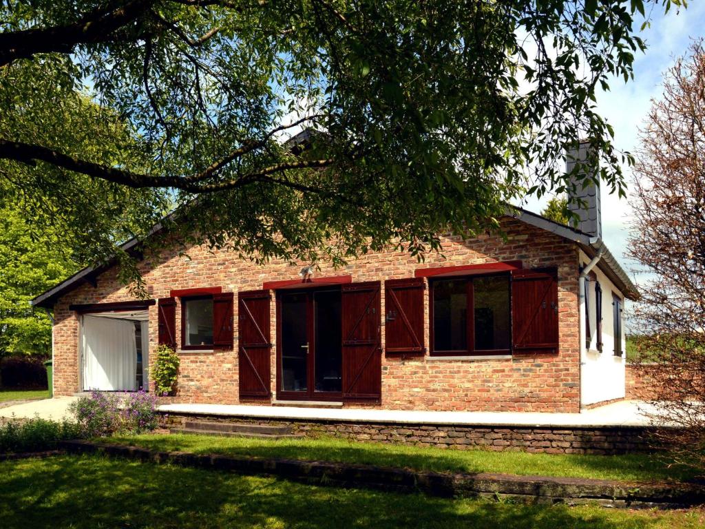 ein Backsteinhaus mit roten Türen und einem Baum in der Unterkunft Cozy bungalow with large enclosed garden in Baillamont