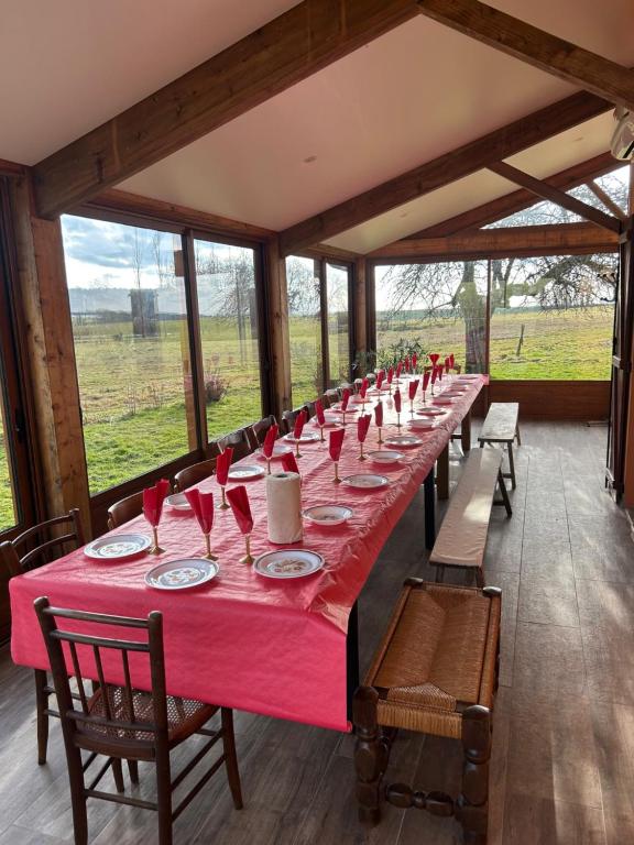 a long table in a room with a red table cloth at Gîte Des Prés Berthe in Le Clerjus