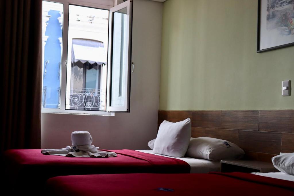 ein Schlafzimmer mit zwei Betten und einem Fenster mit einem Stofftier in der Unterkunft Hotel Teresita in Puebla