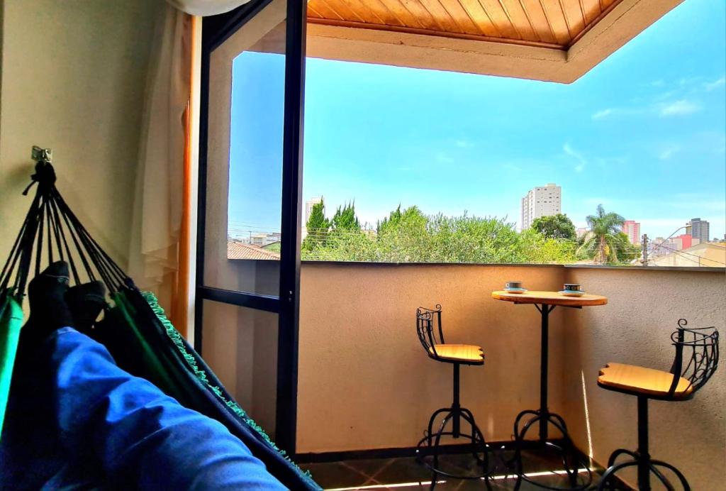 a person laying in a hammock in a room with a window at Aconchego e estilo, apto 2 quartos, próximo a USP in São Carlos