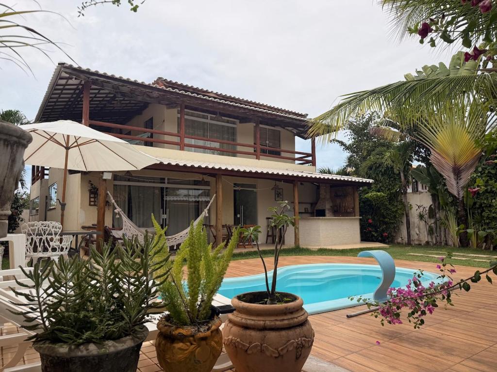 a house with a swimming pool in front of a house at Villa Amarela in Itacimirim
