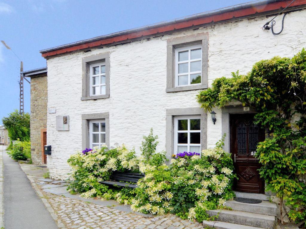 una casa de ladrillo blanco con flores delante en Very authentic Ardennes house, en Paliseul