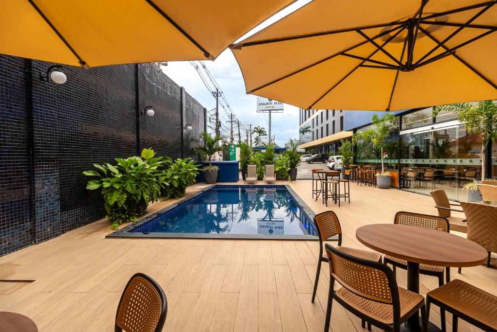 an outdoor patio with tables and umbrellas and a pool at Amazon Park Hotel in Belém