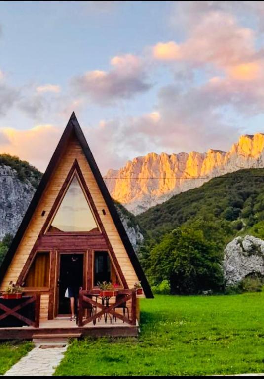 a cabin in a field with a table and a mountain at Etno Cottages Komarnica Authentic Peaceful Mountain Getaway in Šavnik