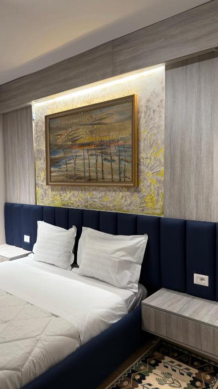 a bedroom with two beds and a painting on the wall at Agora ApartHotel in Tirana