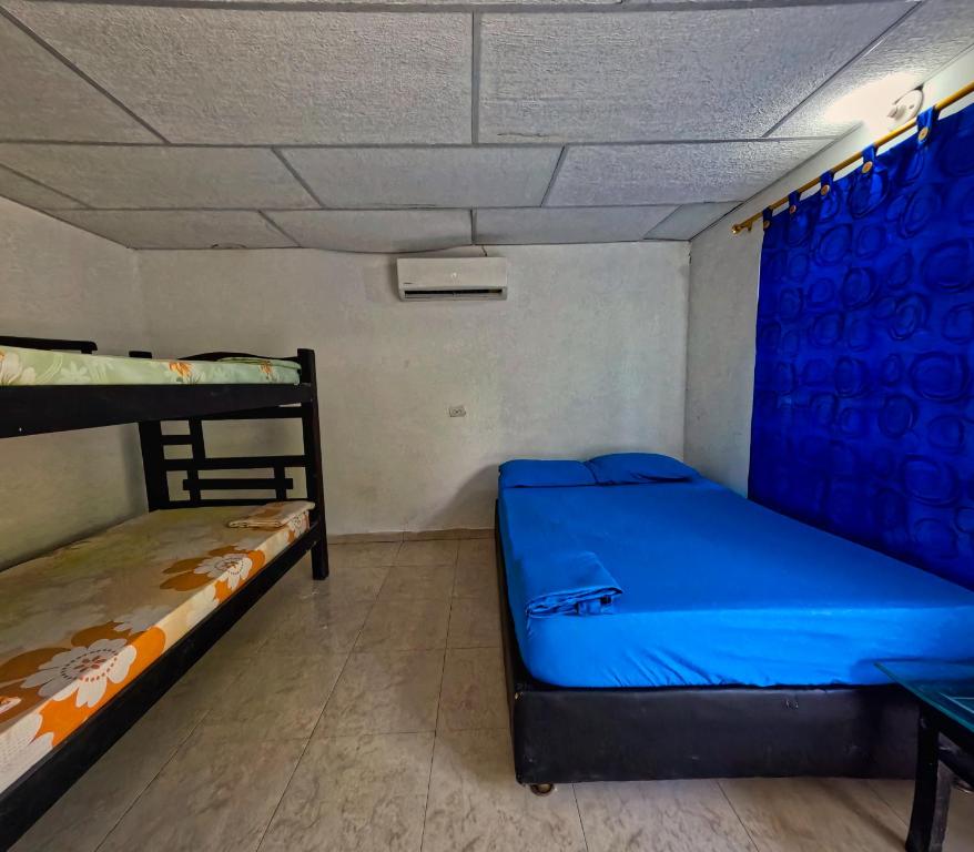 a room with two bunk beds and a blue curtain at Hostal Bahia Bocachica in Cartagena de Indias
