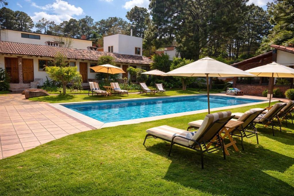 a swimming pool with lawn chairs and umbrellas at Hotel las Caballerizas in Valle de Bravo