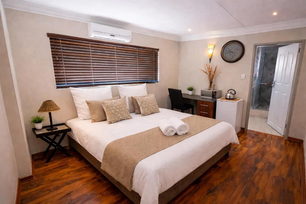 a bedroom with a large white bed and a desk at Caesars Place Guest House in Kathu