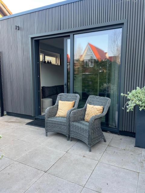 two wicker chairs sitting on a patio with windows at Dishoek by the Sea in Koudekerke