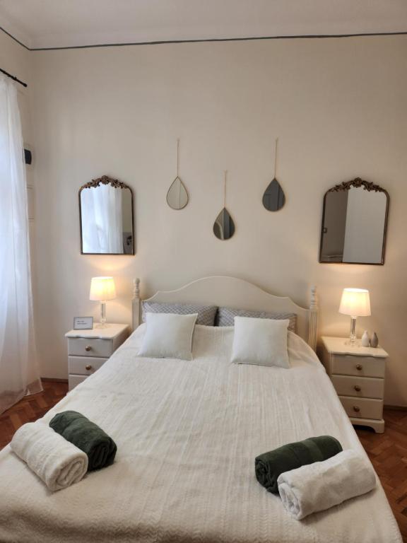 a bedroom with a large white bed with two mirrors at Central old town escape in Timişoara