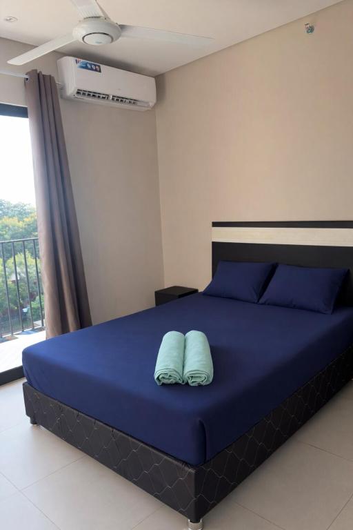 a bedroom with a blue bed with two pillows at Modern Studio with Balcony in Asunción