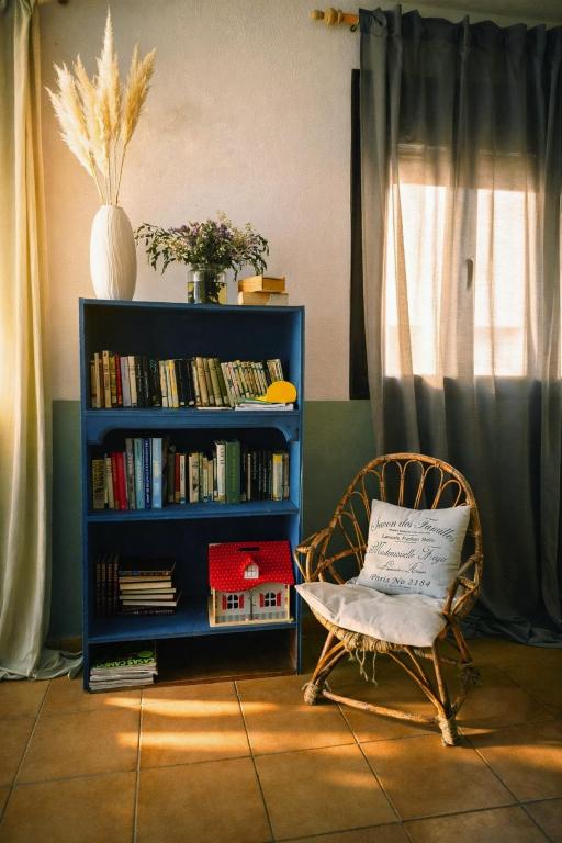 a chair in a room with a book shelf with books at Albergue la Fontanina ALCC00043 in Mata de Alcántara