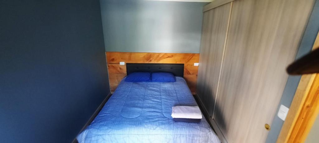 a small bed in a small room with blue walls at Cabaña Guzman in Villarrica