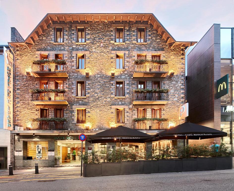 ein großes Backsteingebäude mit Sonnenschirmen davor in der Unterkunft Hotel de l'Isard in Andorra la Vella