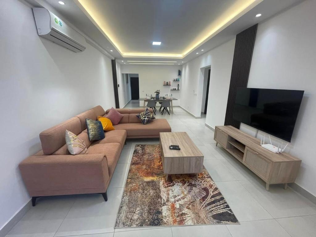 a living room with a couch and a flat screen tv at Voyage d'affaires et séjour paisible in Abidjan