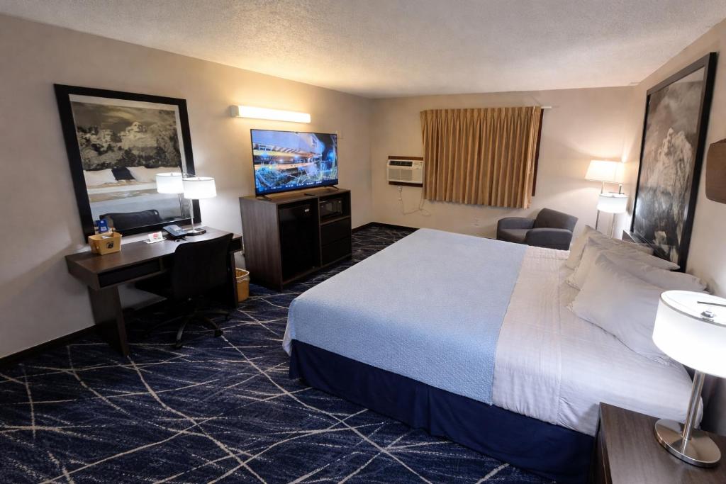 a hotel room with a bed and a flat screen tv at Super 8 by Wyndham Sturgis in Sturgis