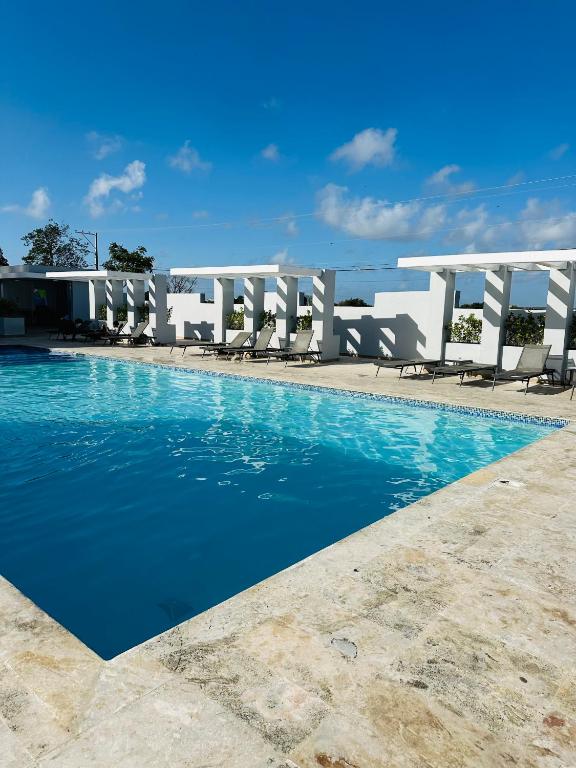 a swimming pool with chairs and blue water at Residencia tropical jardines 3 in Punta Cana