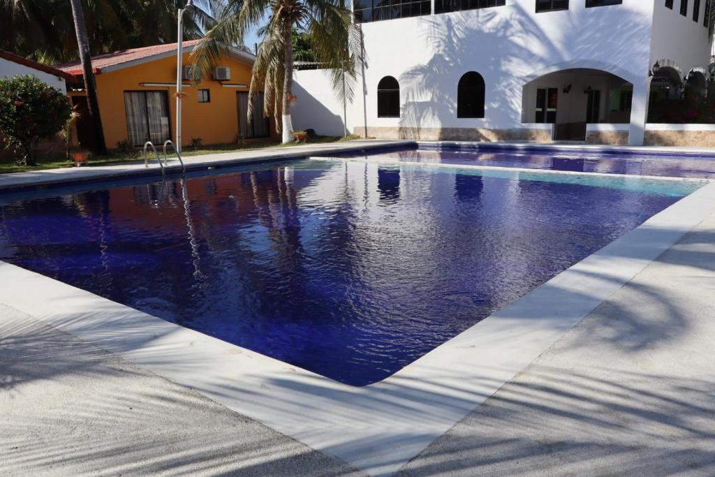 a swimming pool with blue water in front of a building at Habitación en villa Costa del sol in Los Blancos