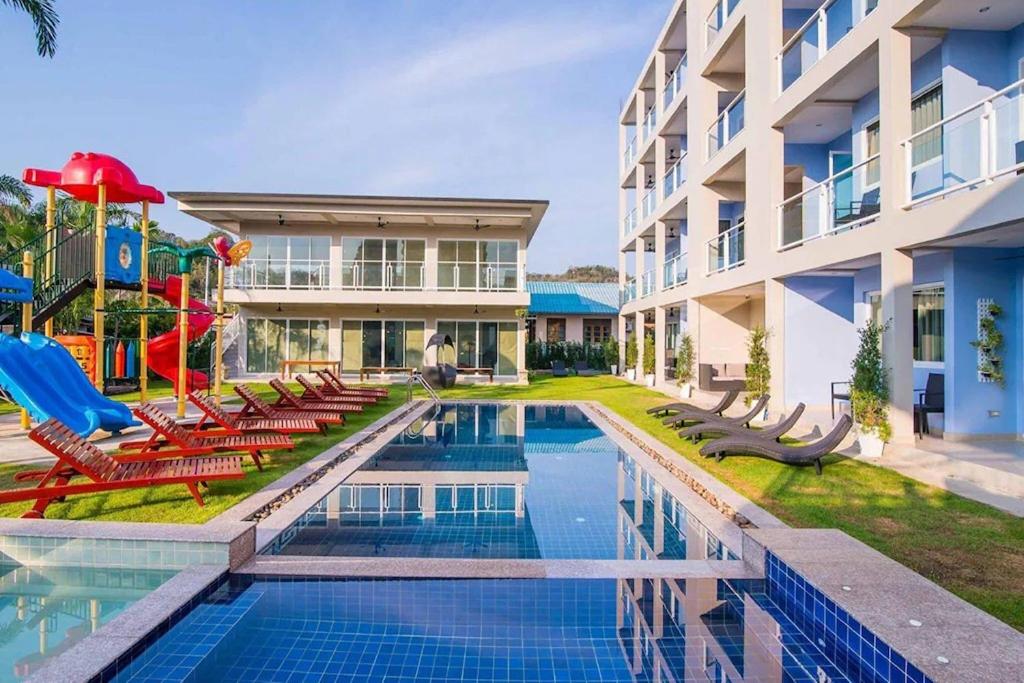 a pool with chairs and a playground next to a building at Surf & Sand Resort in Hua Hin