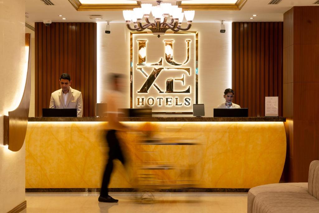 two men sitting at a reception desk in a hotel at Luxe Avenue Hotel in Dubai