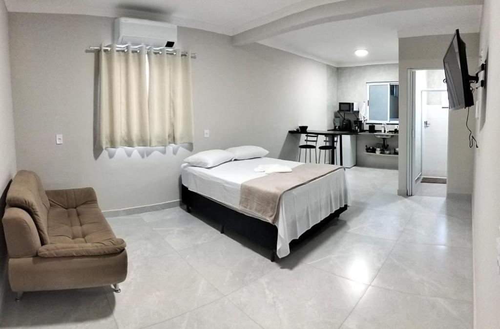 a bedroom with a bed and a chair in it at Kitnet Moderna com Ar e Vaga Privativa Coberta in Votorantim