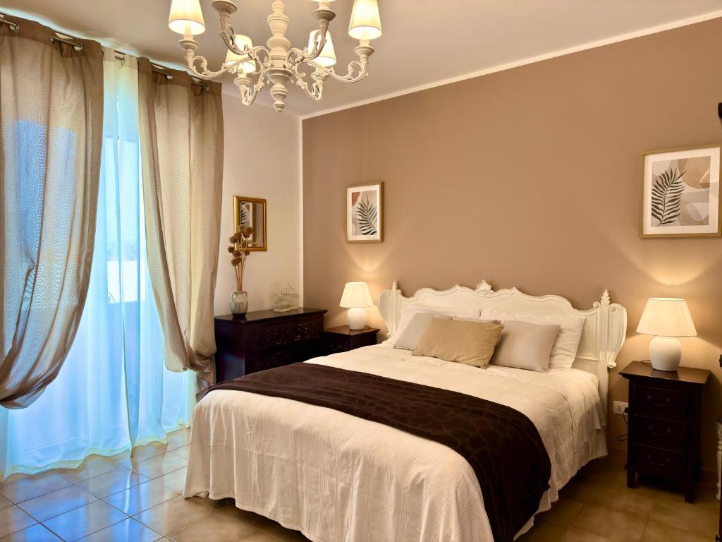 a bedroom with a large white bed and a chandelier at Blue Dolphin Guest House in Alghero