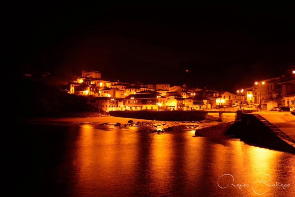 a city lit up at night with a body of water at Apartamentos Rurales Les Mestes in Tazones