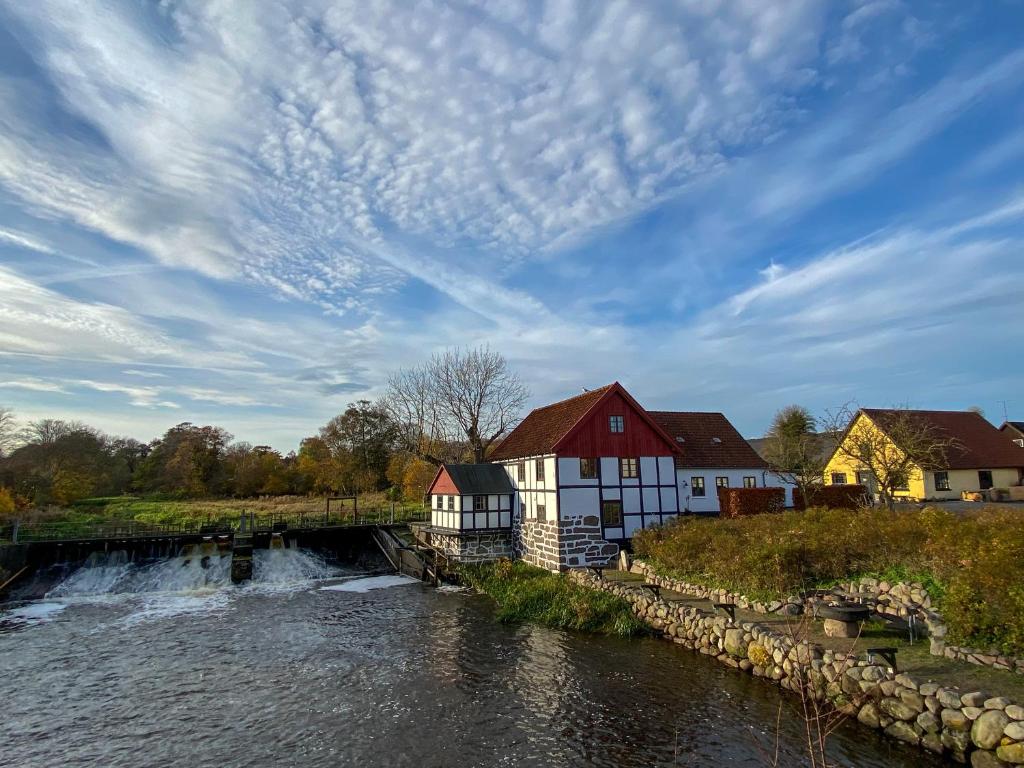 a house next to a river with a waterfall at The Mill House - Saeby Watermill in Sæby