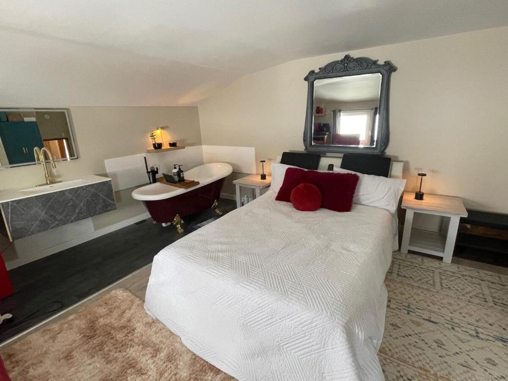 a bedroom with a bed and a bath tub and a sink at Sip and Soak, hotel-style room in Calgary