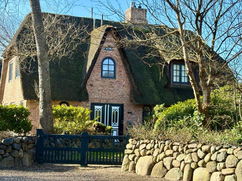 a house with a grass roof with a fence at Salig Hüs in Kampen