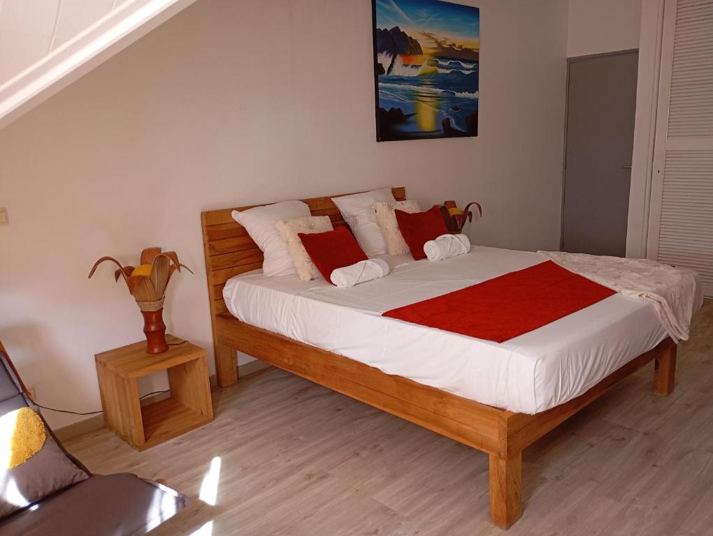 een slaapkamer met een houten bed met witte lakens en rode kussens bij Colibri des îles in Le Gosier