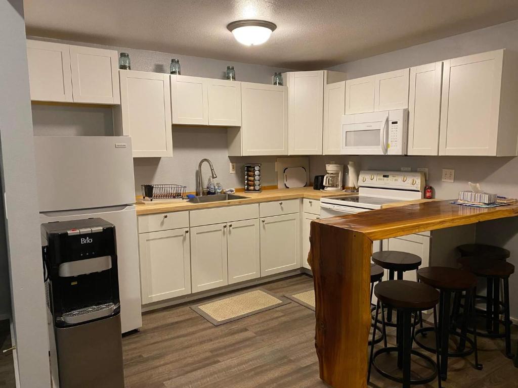 a kitchen with white cabinets and a counter with stools at Rudolph's Reindeer Den in Ketchikan