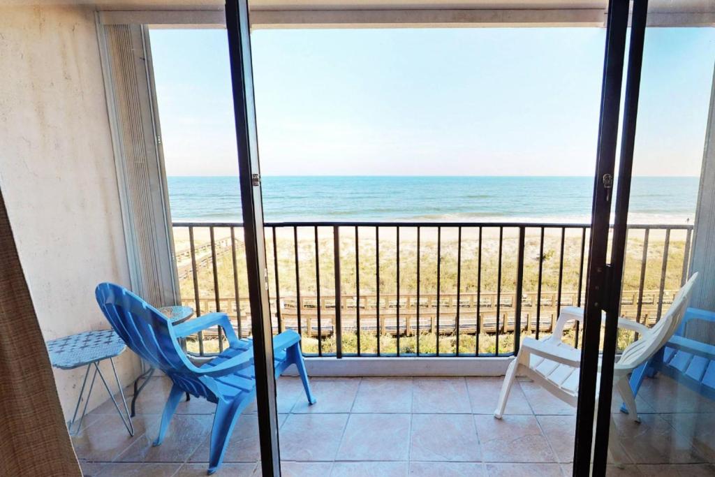 a balcony with chairs and a view of the ocean at Paradise Found in Carolina Beach
