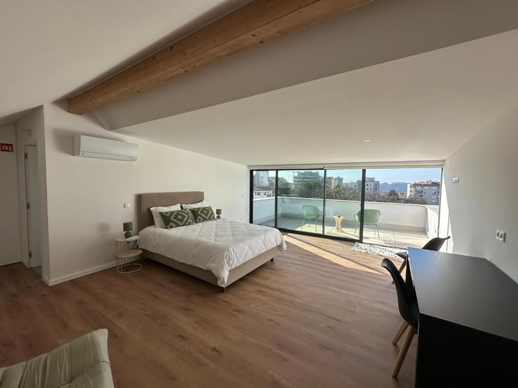 a large bedroom with a bed and a large window at Loft Azeméis in Oliveira de Azemeis