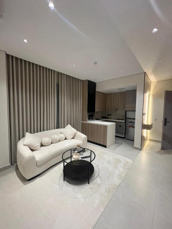 a living room with a white couch and a kitchen at اجنحة راف السلام in Medina