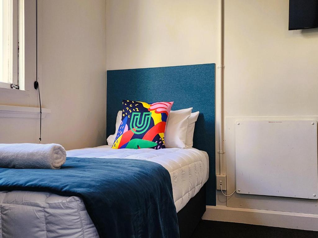 a bedroom with a bed with a blue headboard at Urban Lounge Sleepery Carterton in Carterton