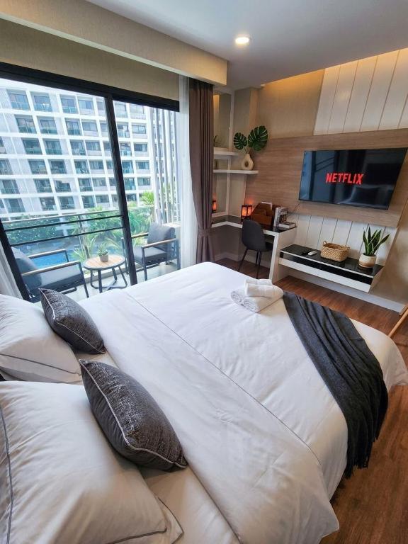 a large white bed in a room with a tv at Dusit Grand Park - Modern Studio Pool View in Jomtien Beach