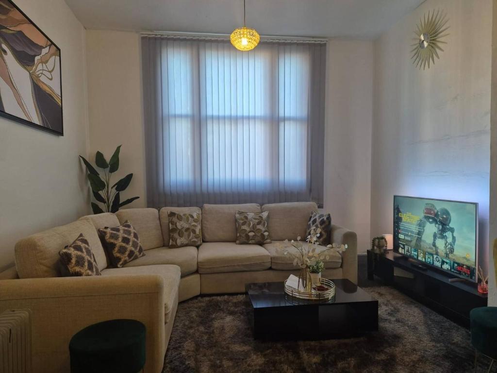a living room with a couch and a tv at Glams one bedroom apartment in Wolverhampton