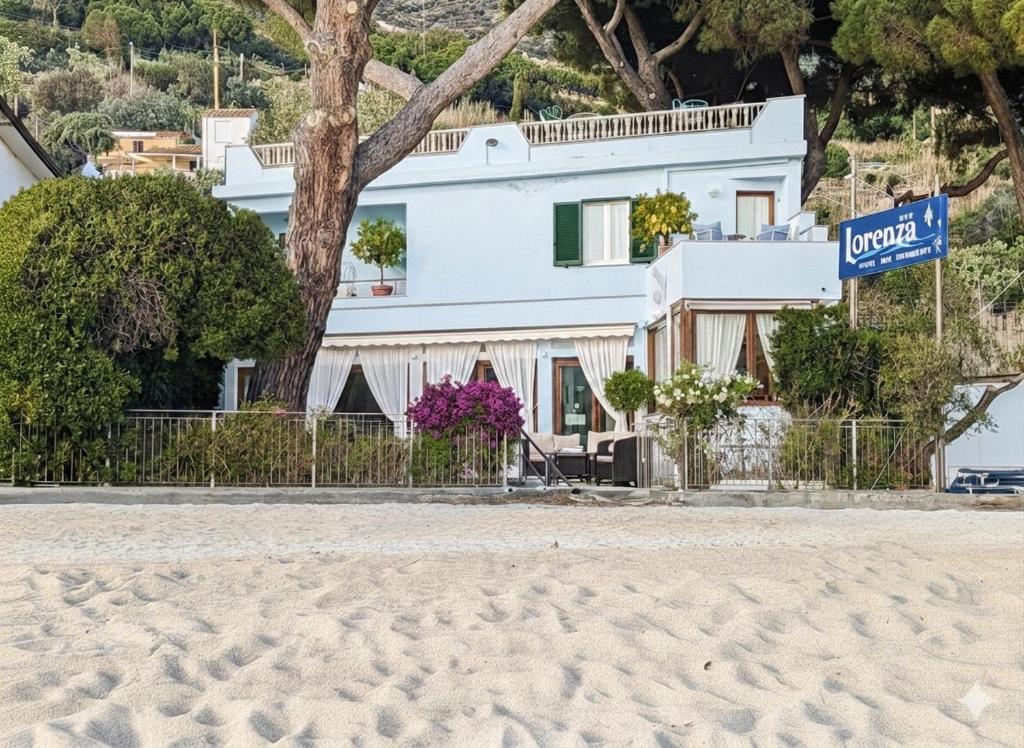 a house on the beach in front of a building at Hotel Lorenza B&B e Mini Suite in Cavoli