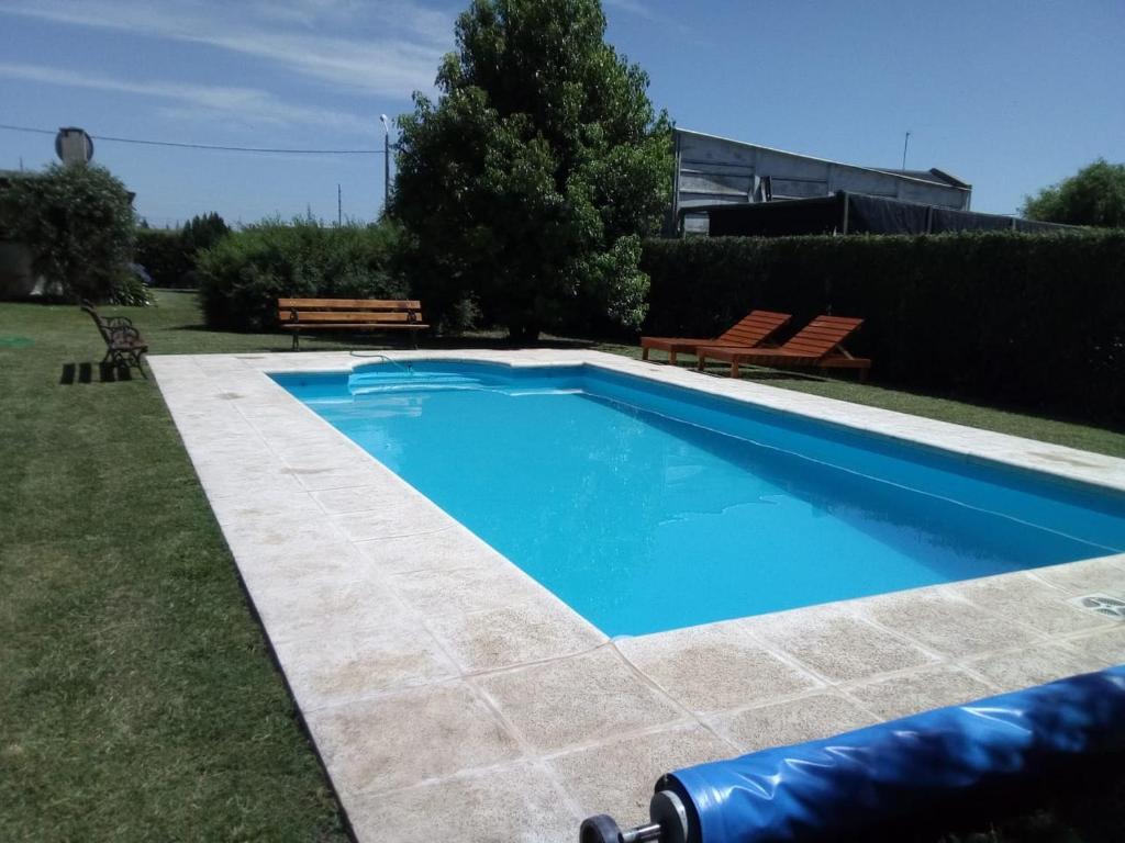 a swimming pool in a yard with two benches at La Calma Casa Quinta in Tandil