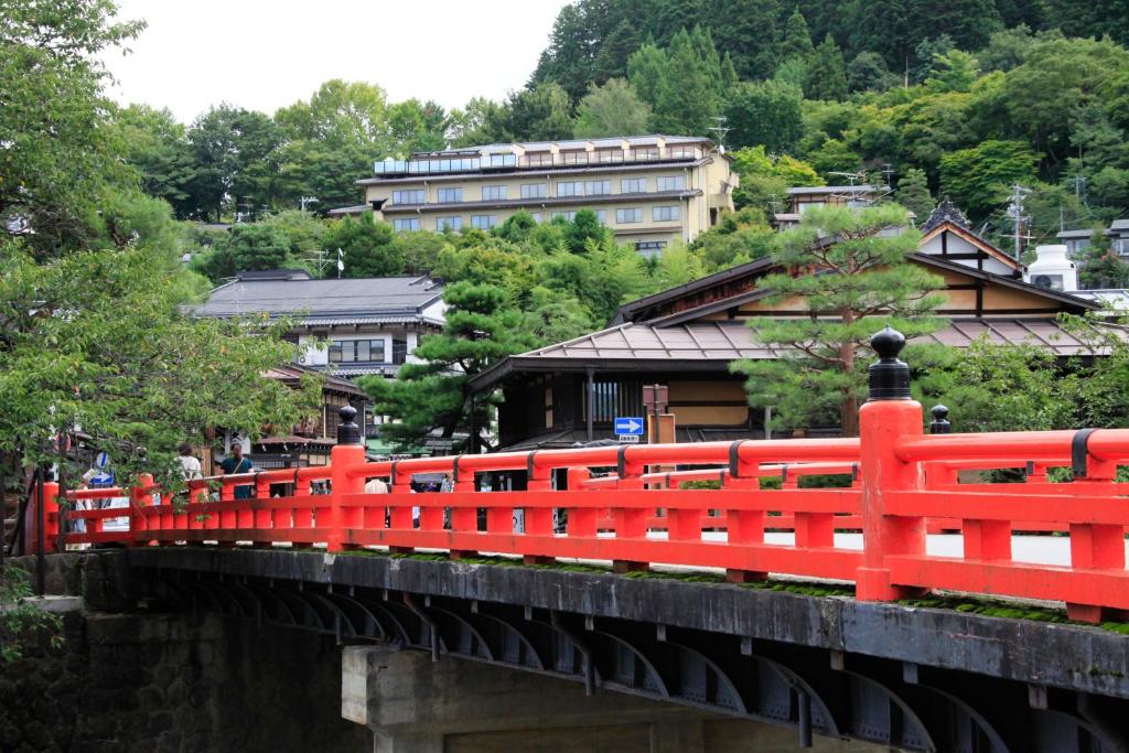 a red bridge over a river with buildings in the background at Hoshokaku in Takayama