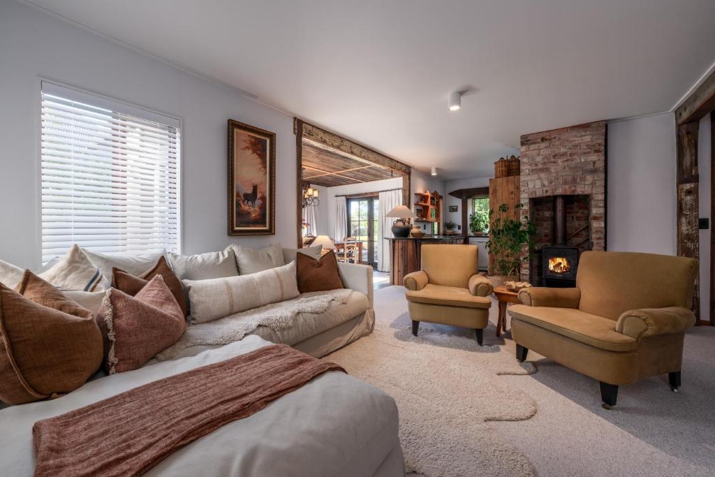 a living room with a couch and chairs and a fireplace at Stone Street Cottage by Sothebys Luxury Rental Homes in Wanaka
